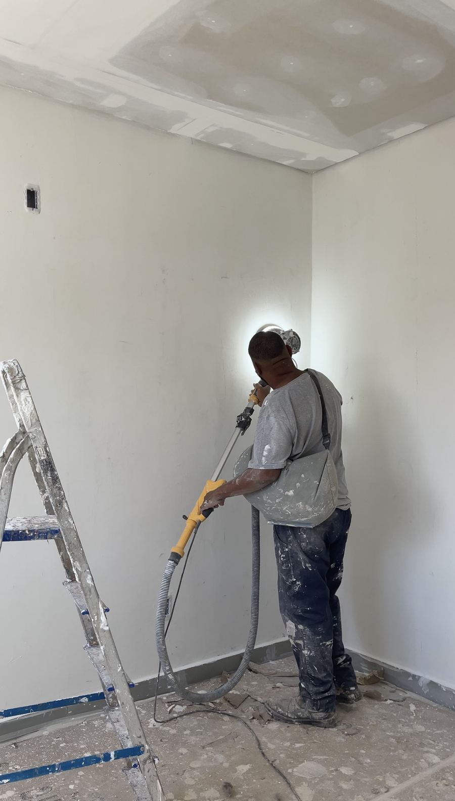 Profissional aplica acabamento na parede de um cômodo.
