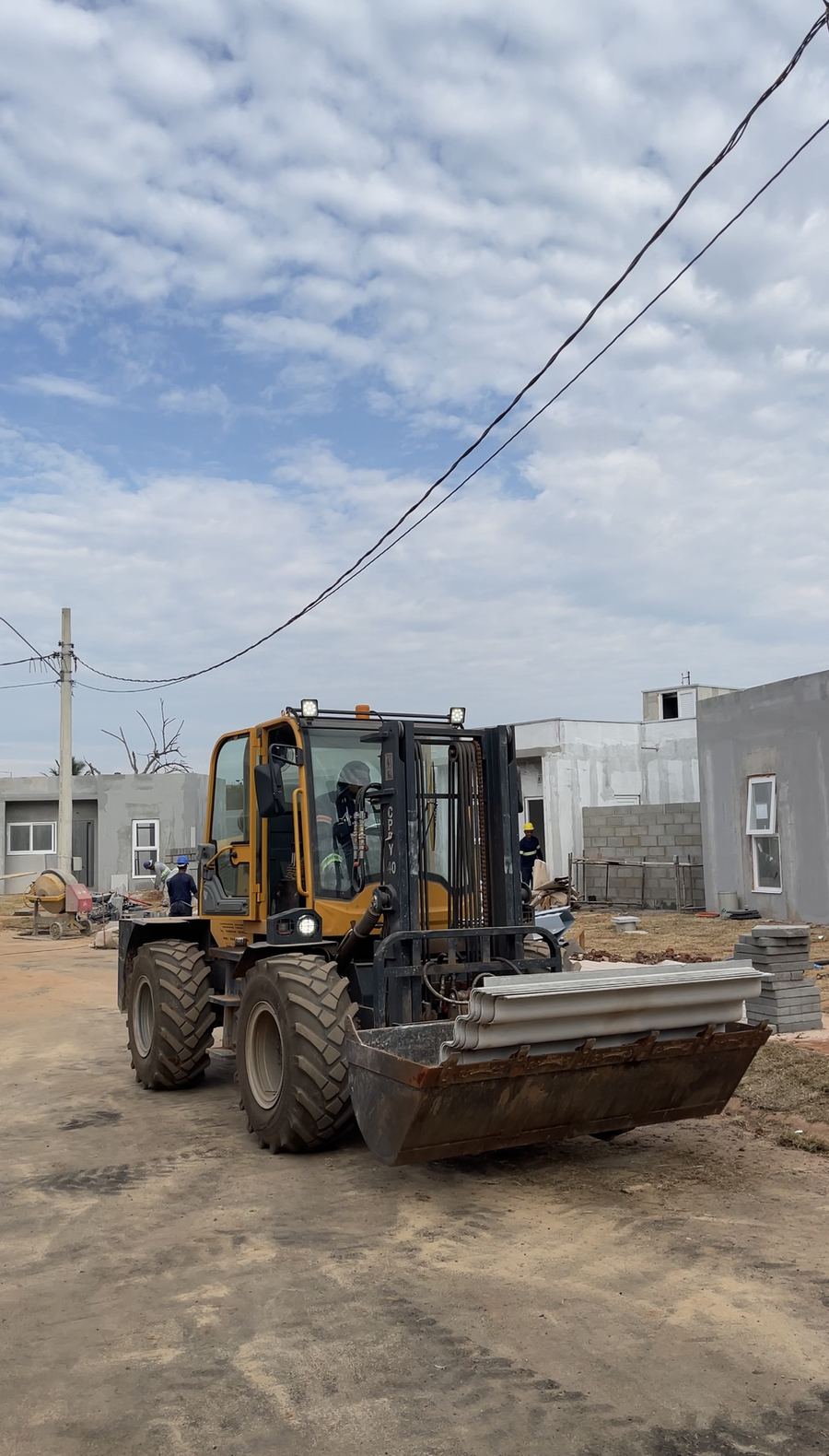 Máquina leva material pela rua do condomínio em obra.