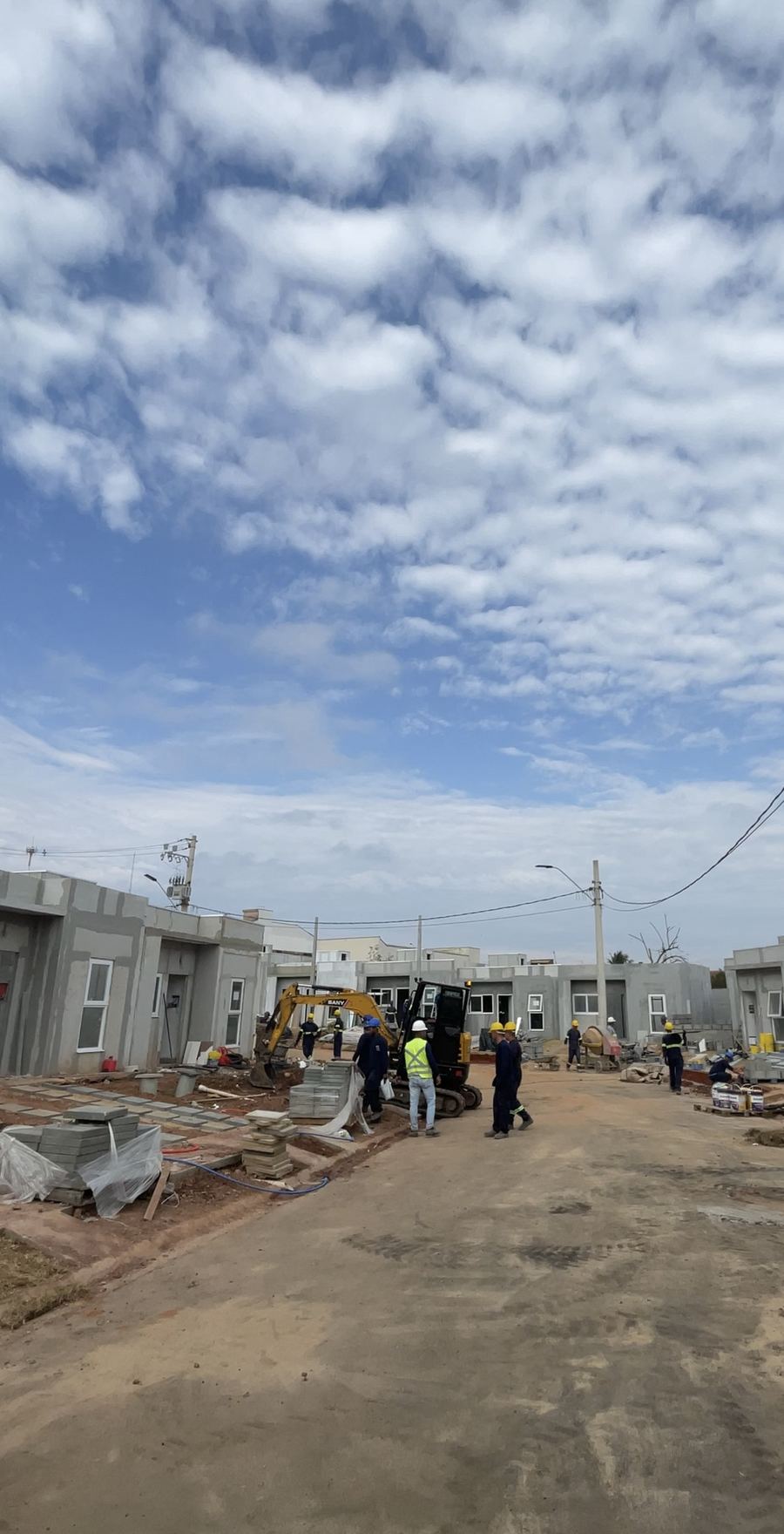 Equipe trabalha na rua entre as casas do condomínio.