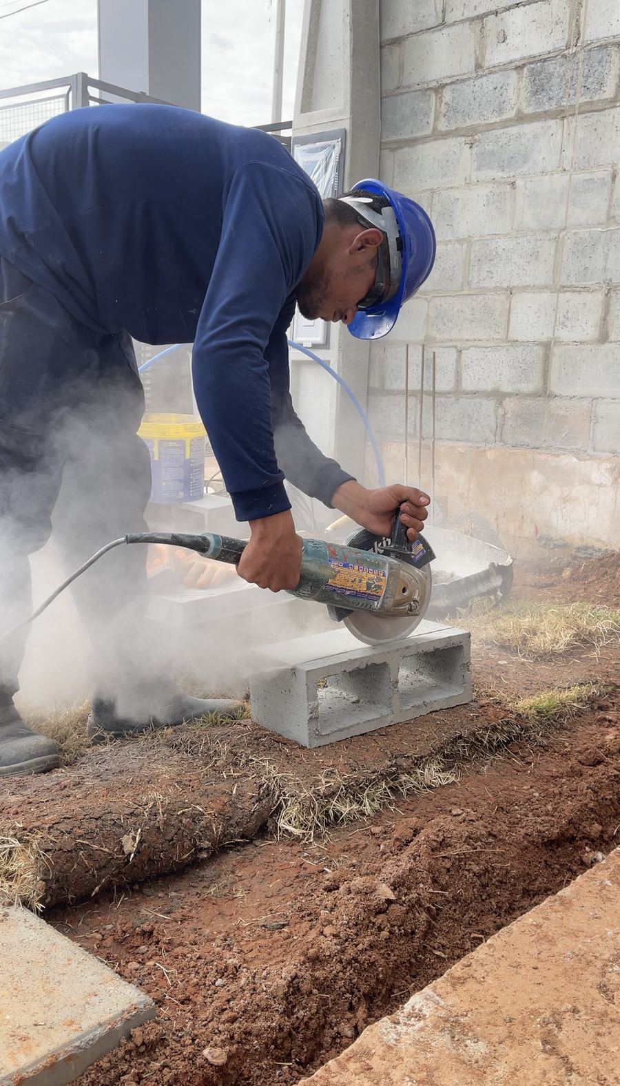 Profissional corta um bloco de concreto com a serra.