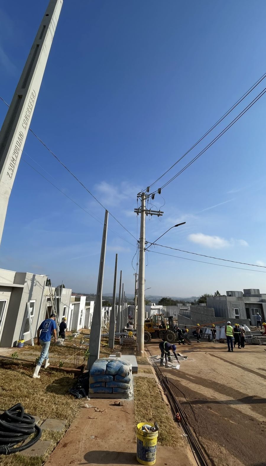 Calçadas e postes sendo instalados ao longo das casas.